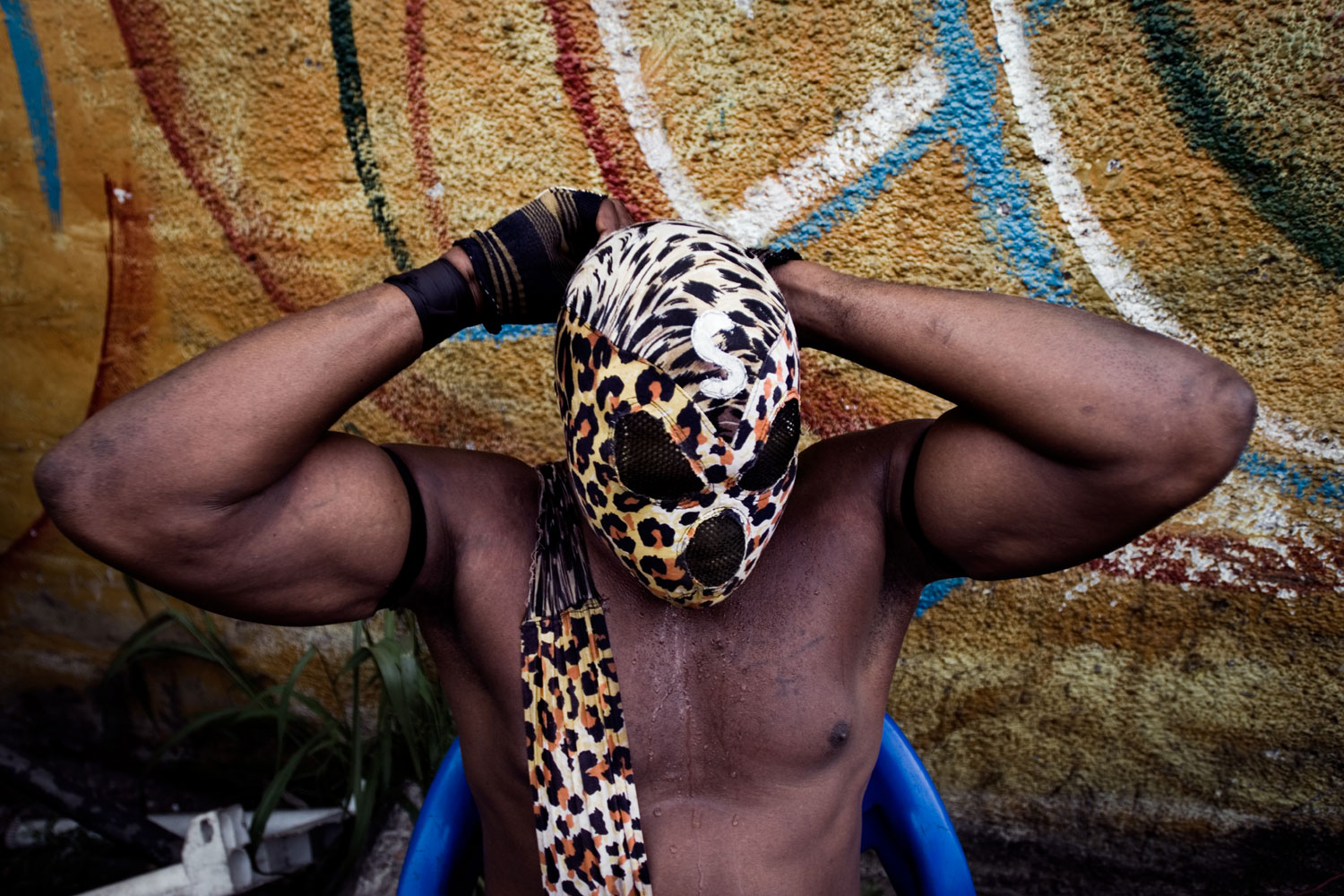 Six Bolites (Six Punches) takes off his mask after the opening procession to a fetish match. Inspired by American wrestling, each athlete has a  gimmick,  a feature that defines him. Six Bolites head butts his opponents, who then run out of the ring and take shelter in a tree until someone breaks the  spell.