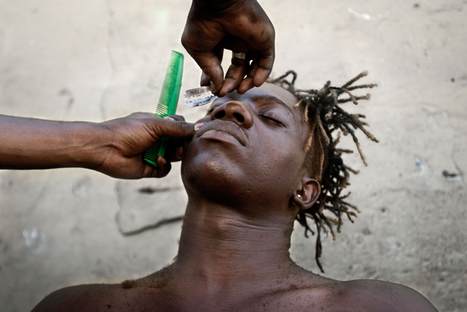 Mabokotomo, a popular young wrestler who competes in fetish and classic matches, is shaved at home in Matete district before a fight. The Congolese place great importance on their looks, and it's especially important for wrestlers to look their best before a fight.