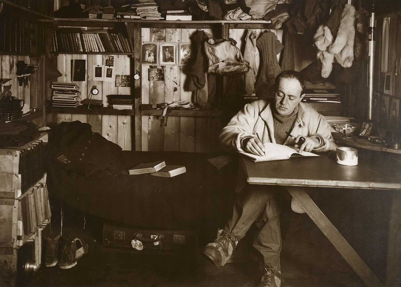 Captain Scott writing in his diary in the corner of his hut at Cape Evans surrounded by his personal belongings on October 7, 1911.