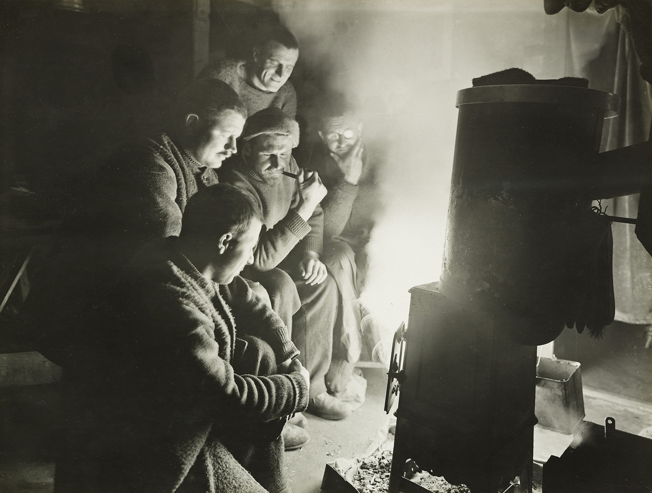 The night watchman, with little to do, apart from observing ice movements, gathers with the men around the fire to share stories in 1915.