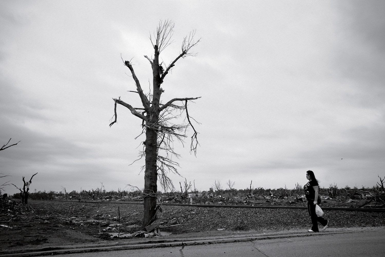 Edward Keating. From  Torn Asunder.  June 6, 2011 issue.
                              
                              Much of Joplin is unrecognizable since the tornado. A woman walks by the railroad tracks near 20th St. on May 24, 2011.
