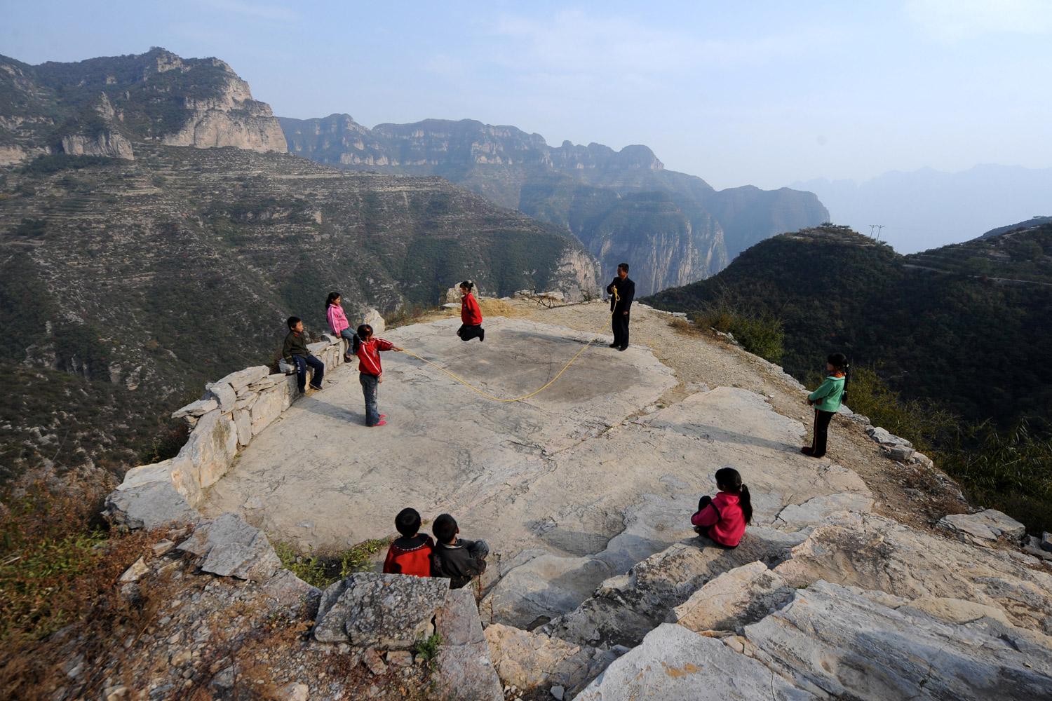 August 9, 2011. Yuan Zichao, principal of Xichan Primary School, plays with students on the ''playground,'' a big stone, in Pingshun, north China's Shanxi Province.There are dozens of ''mini schools'' scattered in the mountainous areas of Pingshun, each having less than 10 people including students and teacher.