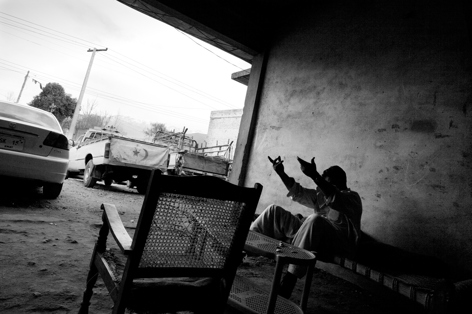 Pakistan, Swat Valley, Kanju, March 2011. Lashkar member Ameer Zaib raising his arms during a joke with one of his colleagues (out of frame) at a car showroom in Kanju. Ameer Zaib works in this showroom to provide for his wife and their two small children, but the trade is not going well in this area still troubled by the aftermath of last year's floods.