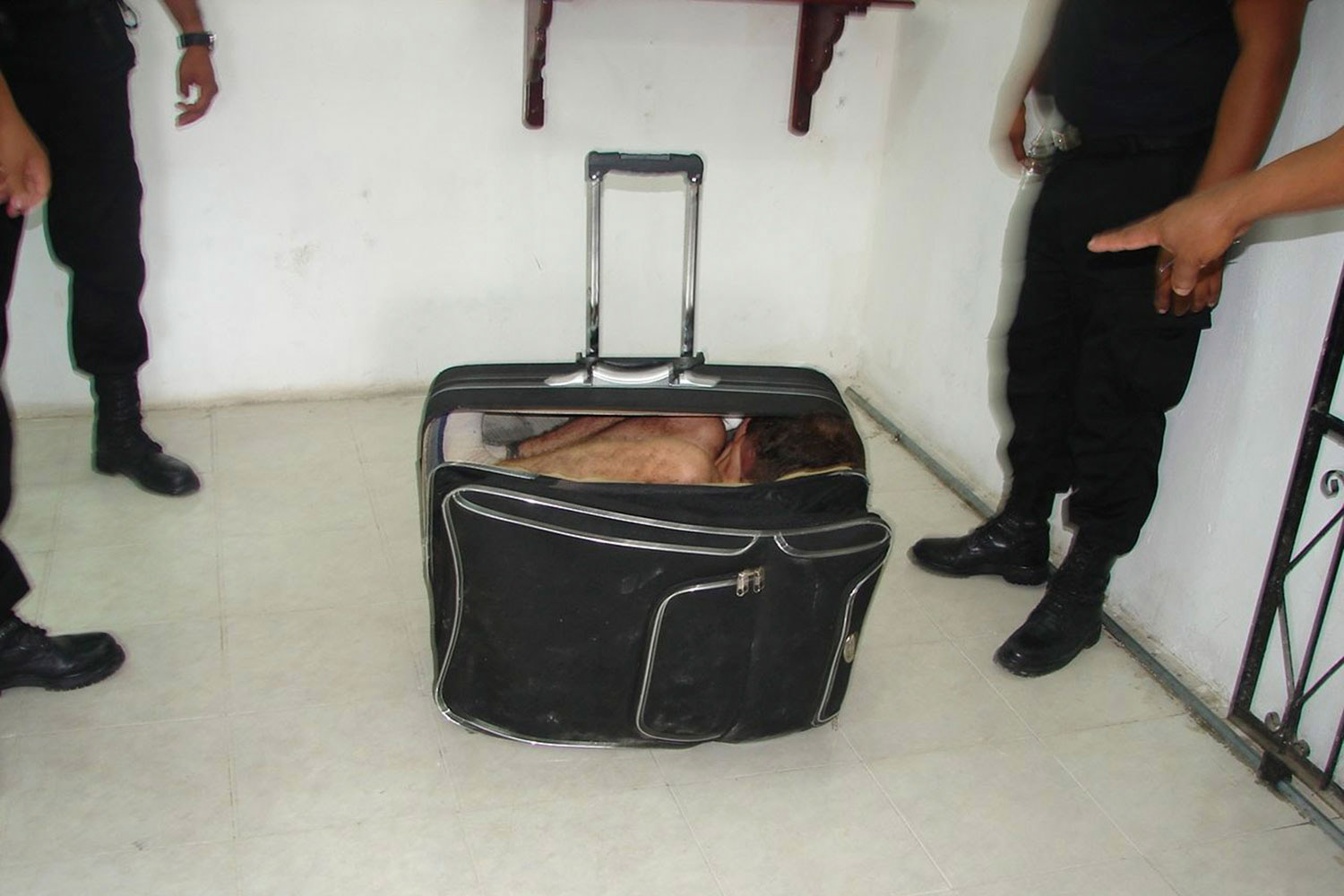 July 2, 2011. Prison guards stand around inmate Juan Ramirez Tijerina as he hides in a suitcase during an escape attempt from a prison in Chetumal. Tijerina tried to escape from prison by hiding inside the suitcase after a conjugal visit.