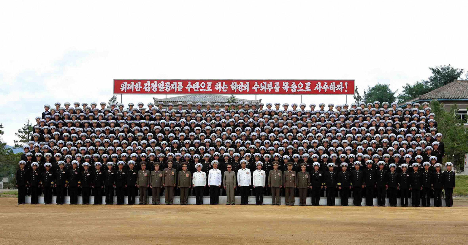 This undated picture, released by KCNA on Sept. 13, 2009, shows Kim Jong Il (center, in sunglasses) posing with the Navy's Combined Unit 597.