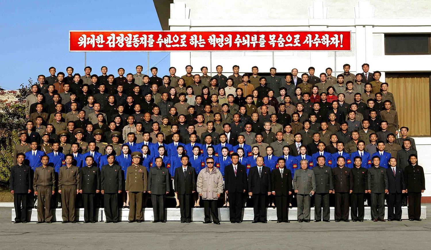 This undated photo, released by KCNA on Oct. 25, 2009, shows Kim Jong Il (center, in sunglasses) posing with staff of the Youth Electric Complex in Huichon.