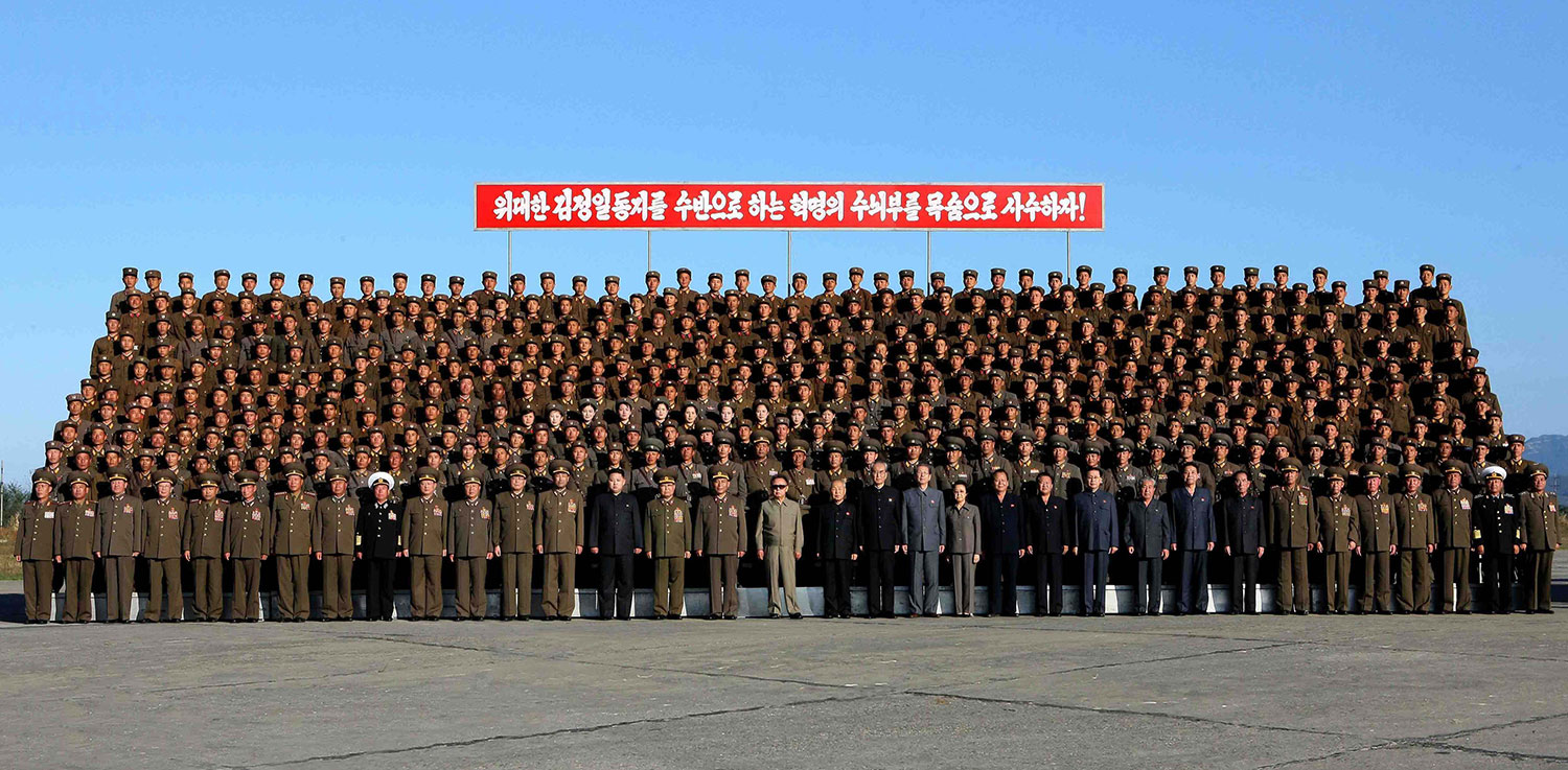 In this undated photo, released on Wednesday, Oct. 6, 2010 by KCNA, Kim Jong Il (center, in sunglasses), and his third son Kim Jong Un (standing three places to his left) pose with soldiers who participated in a coordinated drill at an undisclosed location in North Korea.