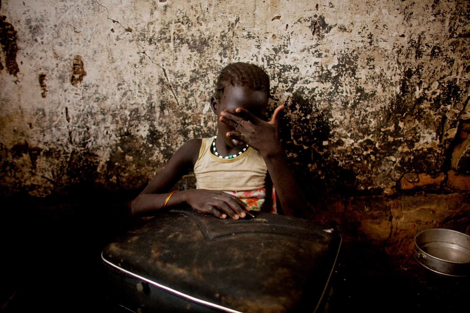 May 26, 2011. Atong Aken, age 9, weeps while clutching a suitcase in a makeshift internally displaced persons camps in Mayan Abun, southern Sudan. While fleeing heavy fighting in the border town of Abyei, Atong became separated from her mother. Heavy fighting and the rapid exodus from Abyei left many families separated. Tens of thousands fled heavy fighting in the hotly contested border town earlier this week during an offensive that left the northern Sudanese military in effective control.