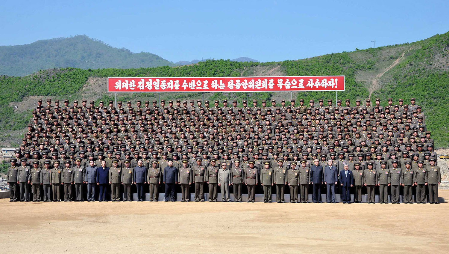 In this undated photo, released by KCNA on May 28, 2011, Kim Jong Il (center, in sunglasses) and his son Kim Jong Un (four places to his left) pose with military personnel working at the construction site of the Huichon Power Station in Jokang Do.