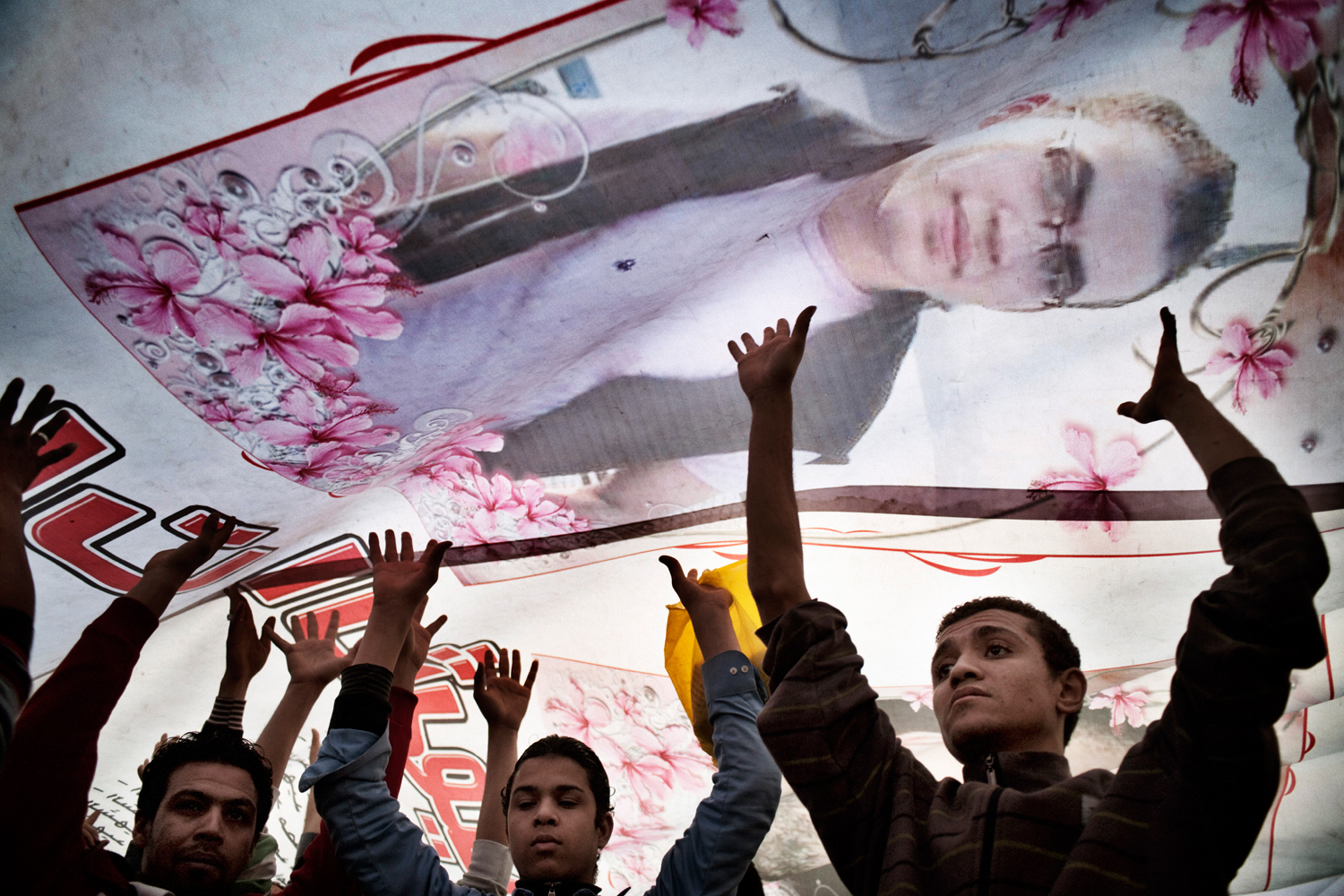 Cairo, Egypt — February 11, 2011
                              Anti-government protesters walk under a banner showing portraits of fallen protesters in Tahrir Square.
