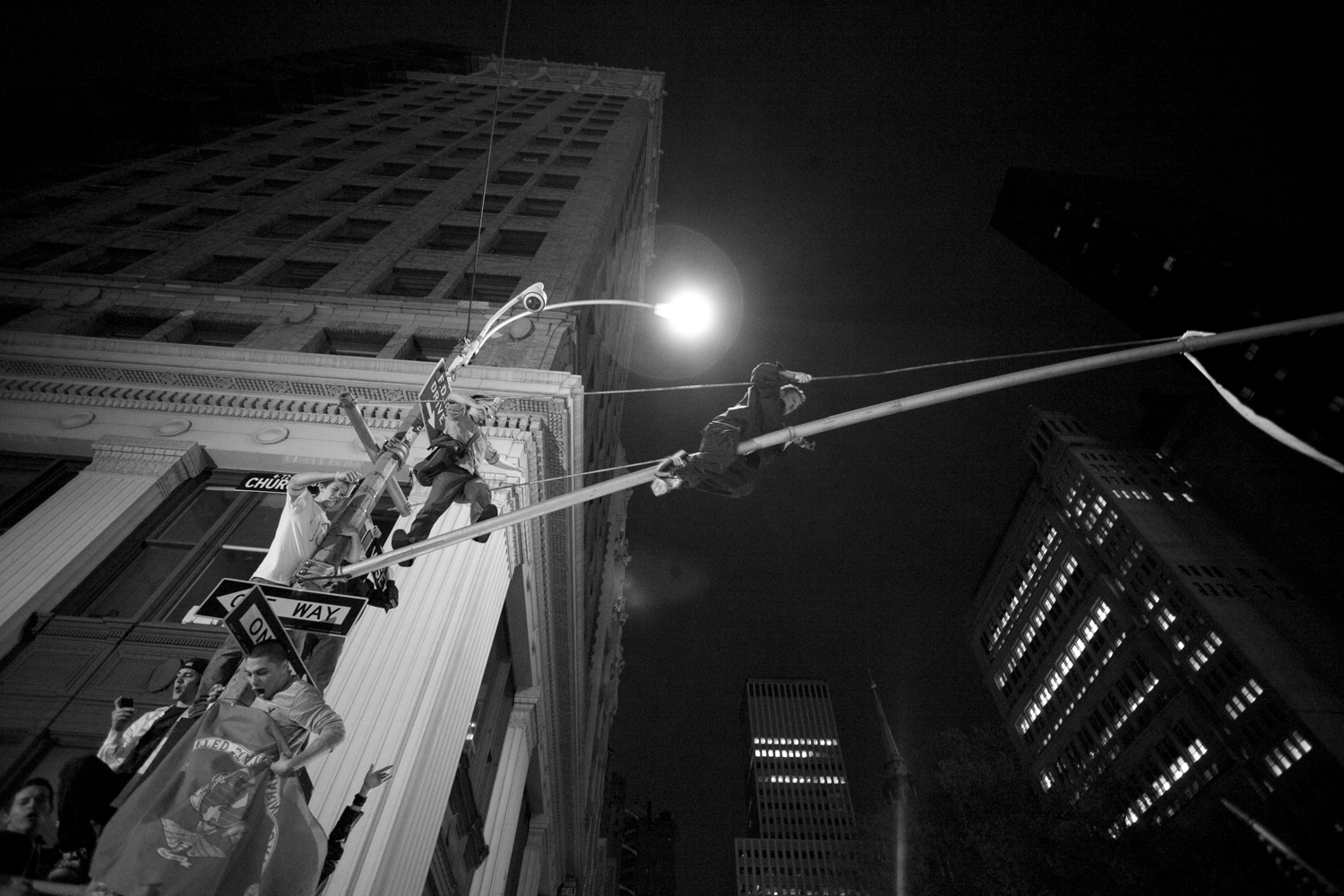 Lauren Fleishman. From  Revelry and Requiem.  May 20, 2011 issue.A crowd gathered at New York's Ground Zero right after Obama's speech announcing the death of Osama Bin Laden on May 1, 2011. Revelers in the crowd scrambled up light poles over the cheering crowd.
