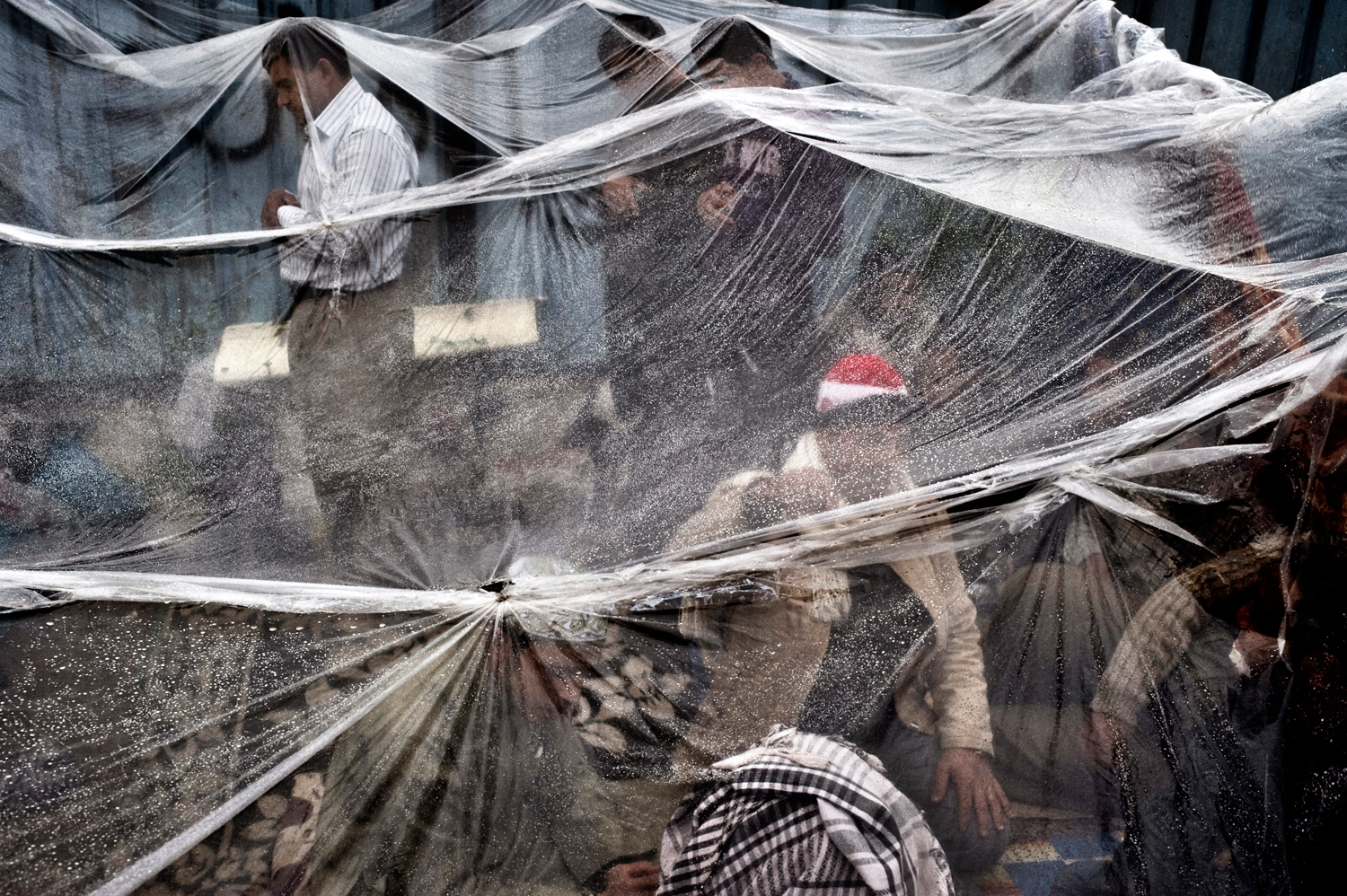 Cairo, Egypt — February 6, 2011
                              Anti-government protesters take refuge from the rain under a plastic tarp in Tahrir Square.