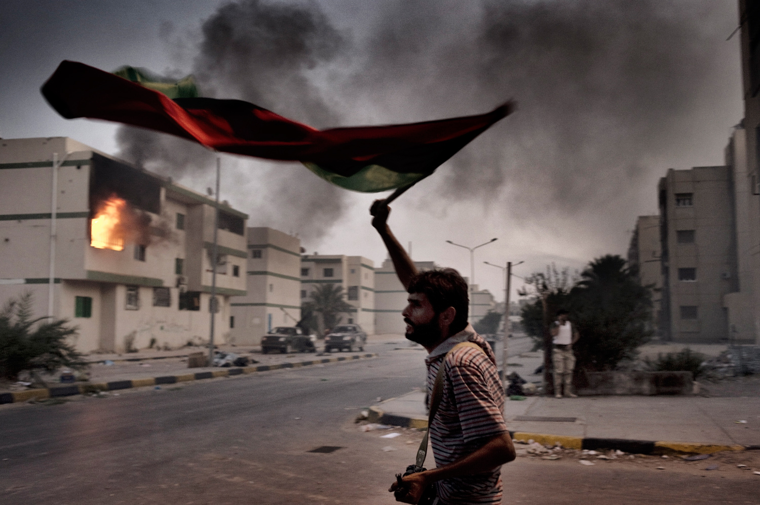 Tripoli, Libya — August 25, 2011
                              A rebel fighter waves the new Libyan flag after intense battles in the Abu Slim neighborhood.