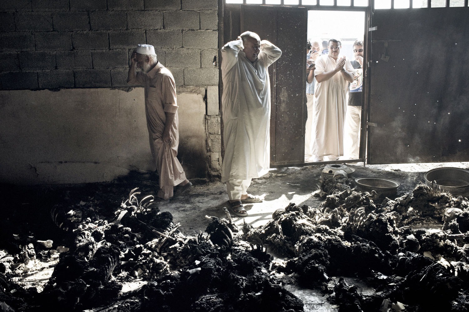 Yuri Kozyrev. From  The Savage and the Strange.  September 12, 2011 issue.
                              A rebel fighter walks inside a warehouse containing the remains of at least 50 burned bodies in Tripoli, Libya on August 28, 2011. A survivor said they were civilians killed by pro-Gaddafi soldiers.