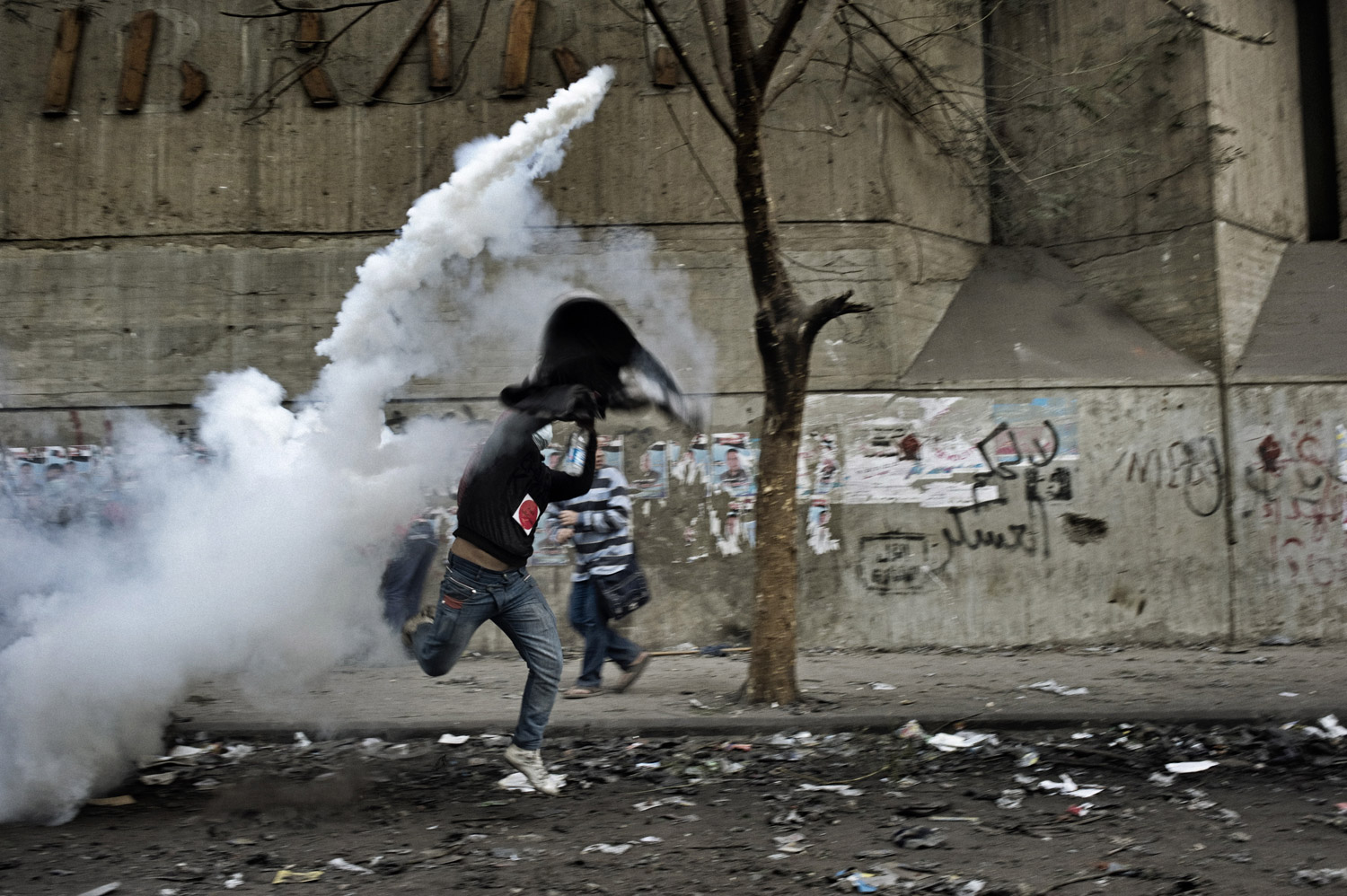 A protester slings a tear gas canister towards Egyptian security forces during clashes, November 23, 2011.