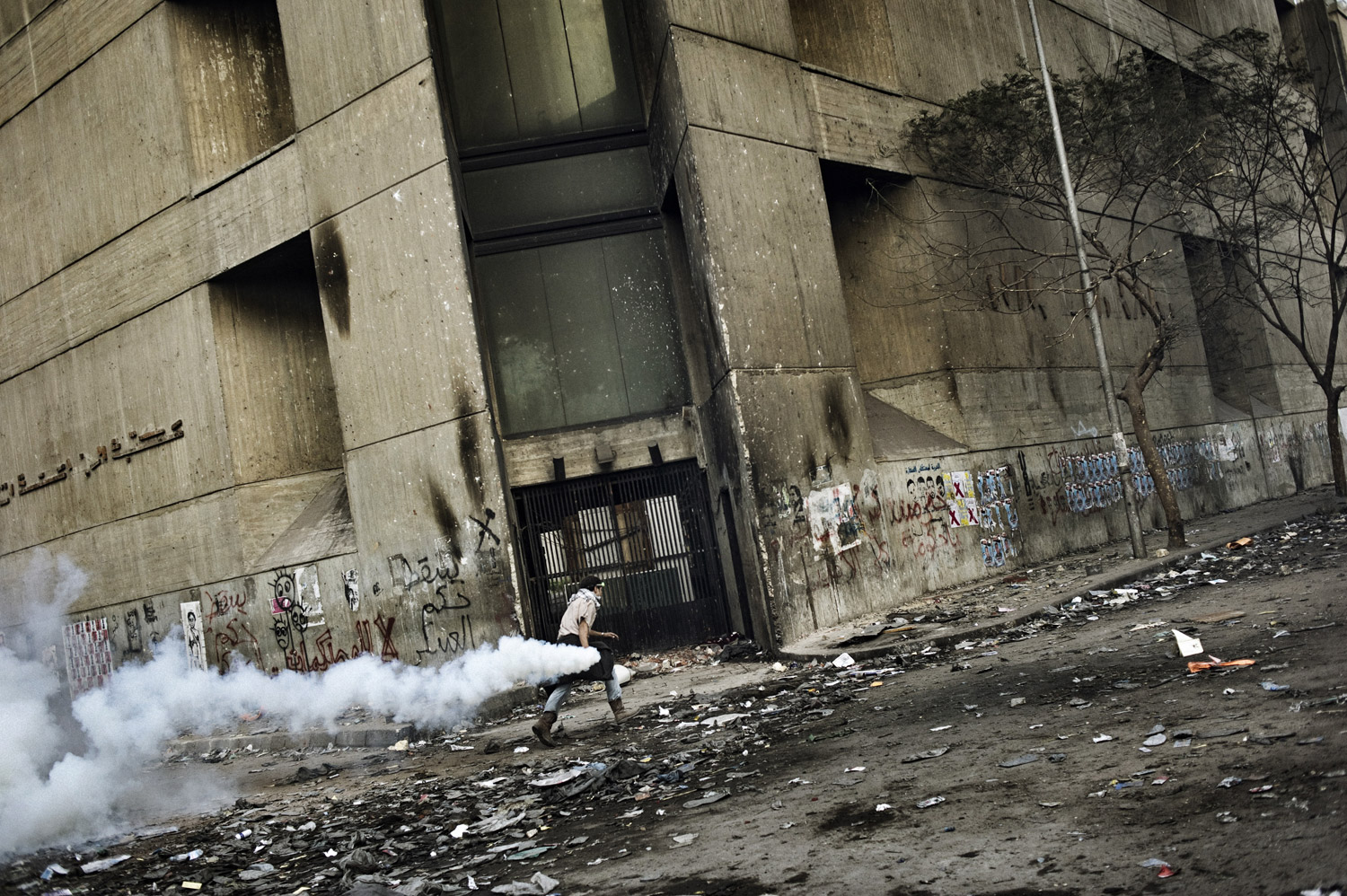 A protester runs with a tear gas canister along Mohamed Mahmoud street, November 23, 2011.