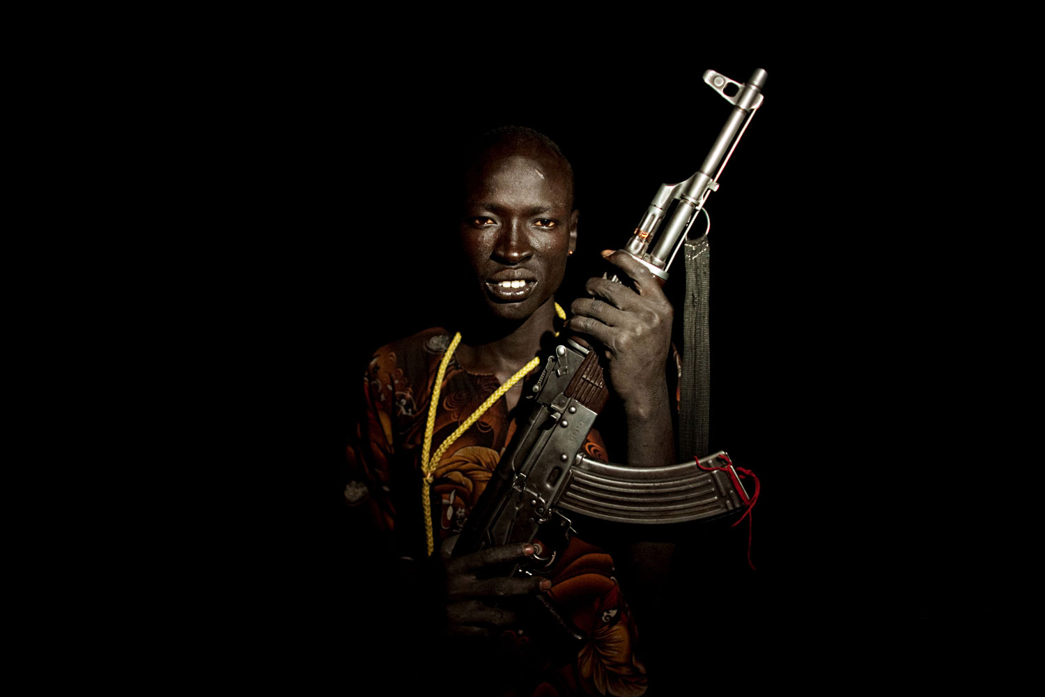 Portrait #5
                              April 21, 2011.  A young cattle keeper from the Dinka Rek sub-tribe poses for a portrait in a remote cattle camp in Wunlit County, southern Sudan. He holds an AK 47 assault rifle, a common weapon among young cattle keeping males.