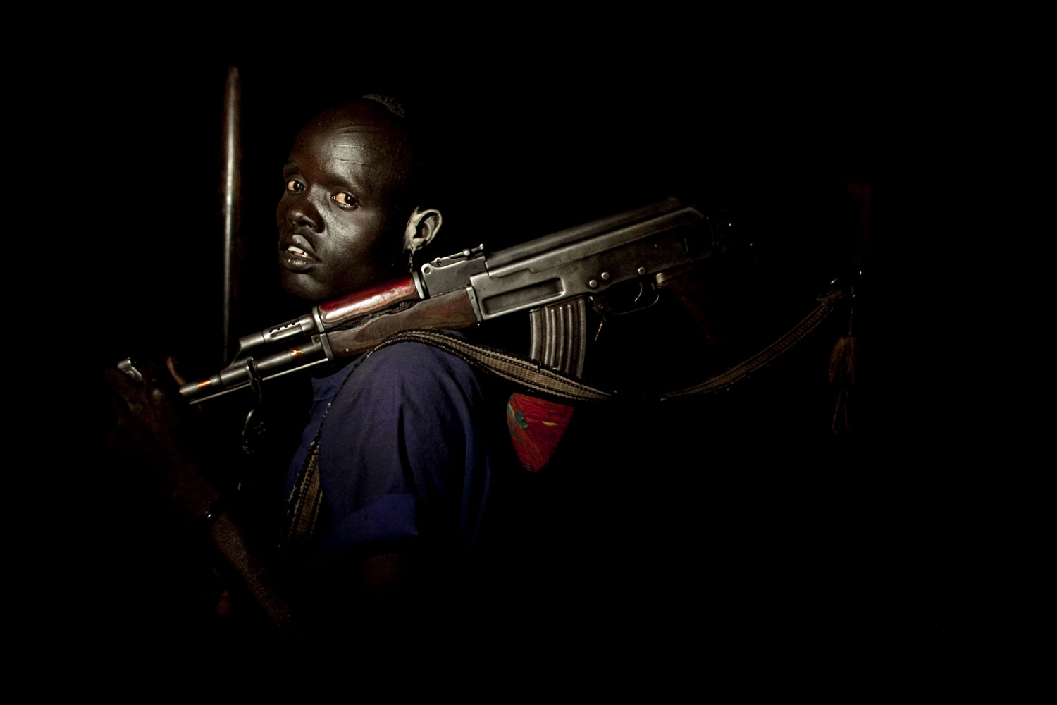 The following six images are from a series Muller shot on young cattle keepers from the Dinka Rek sub-tribe.
                              
                              Portrait #1
                              April 21, 2011. A young cattle keeper from the Dinka Rek sub-tribe poses for a portrait in a remote cattle camp in Wunlit County, southern Sudan. He holds an AK 47 assault rifle, a common weapon among young cattle keeping males. Young men like this man are often tasked with protecting cows from raids by neighboring communities. This image was made at the border between southern Sudan's Lakes and Warrap states where cross-border cattle raiding is extremely common.