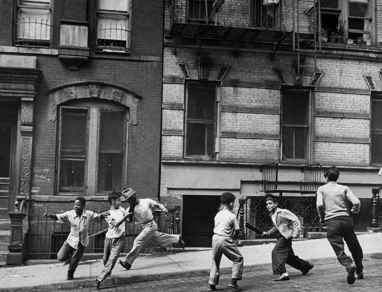 Young boys with sticks run around while playing a street game in Spanish Harlem in January 1947.