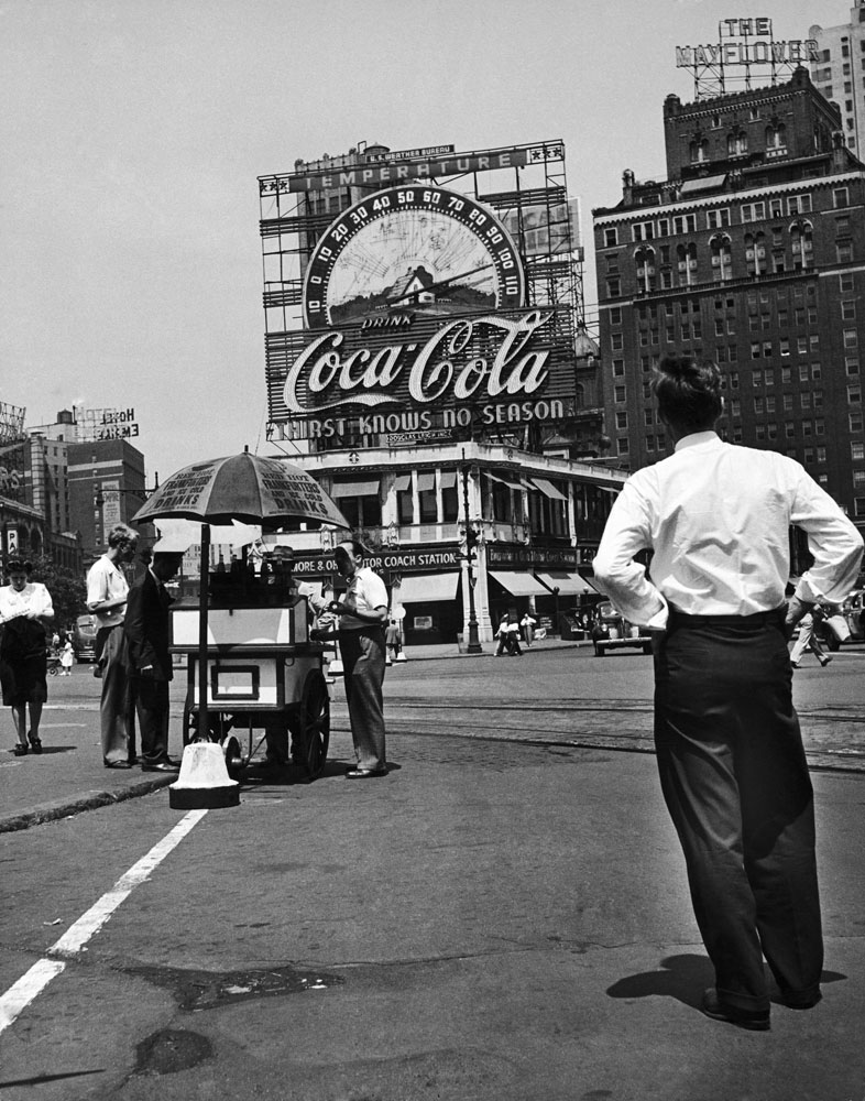Columbus Circle during a heat wave in August 1944. A large Coca Cola sign and thermometer registers 100 degrees on top of building next to the Mayflower Hotel, New York.