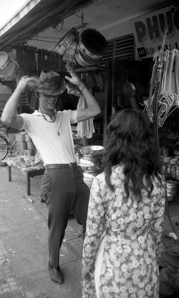 James Farley takes a fancy to a bush hat and models it in the street, Da Nang, March 1961.