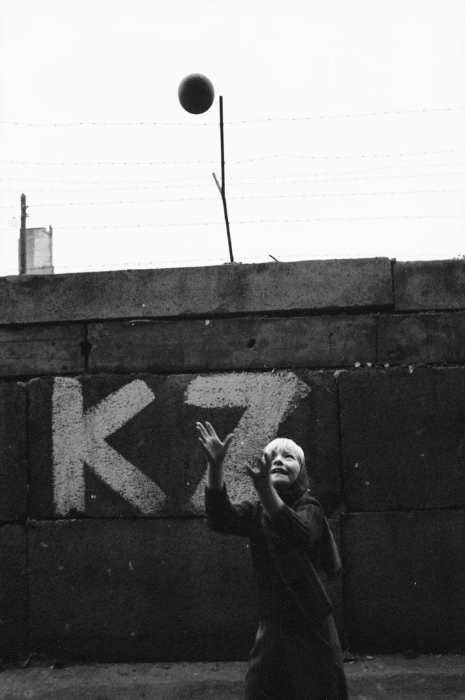 A girl plays with a ball at the Berlin Wall.