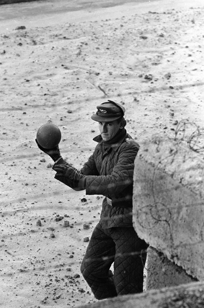 An East German guard throws a ball back to a child on the West German side of the Berlin Wall in 1962.