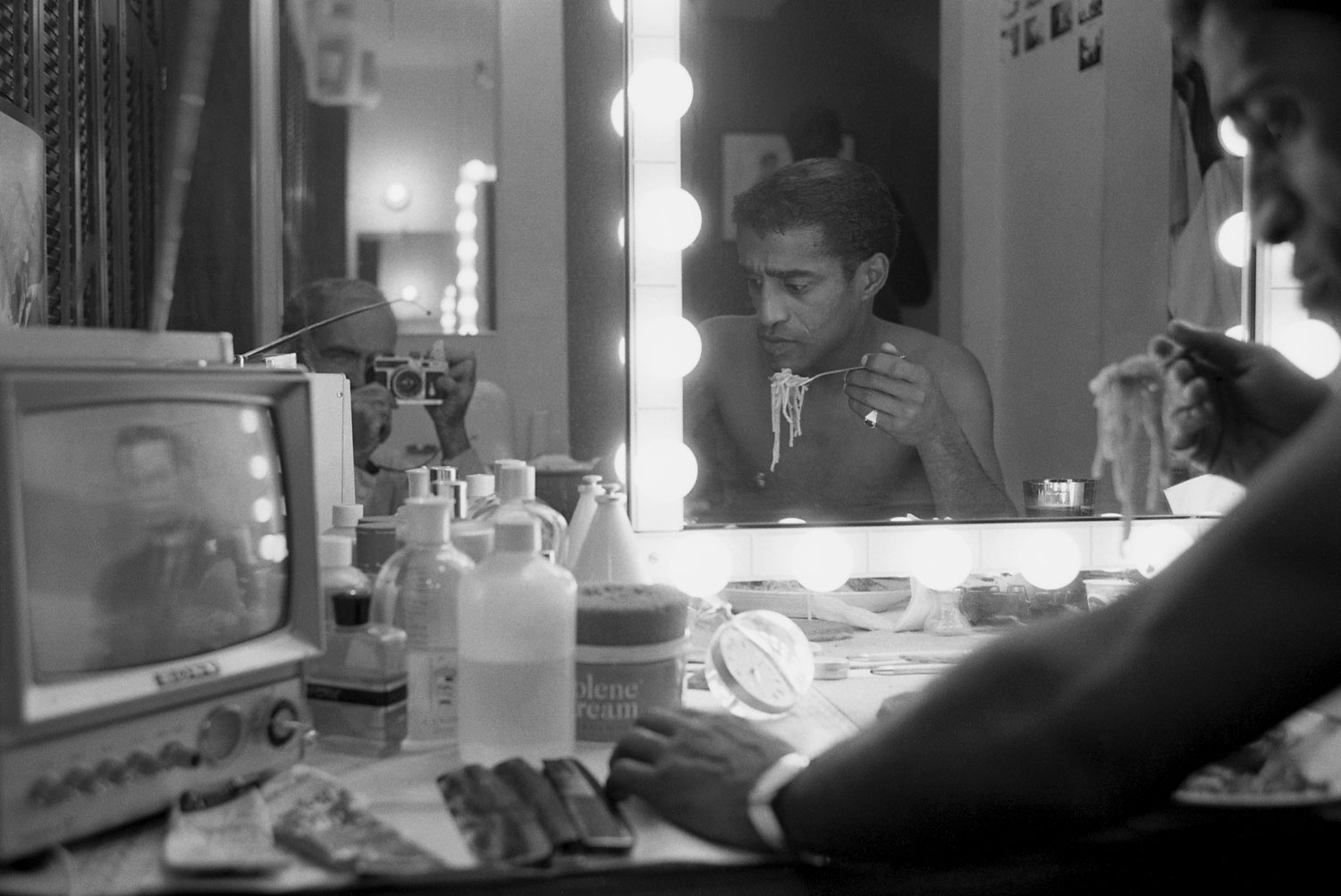 Sammy Davis Jr. eats spaghetti in his backstage dressing room in Golden Boy. Photographer Leonard McCombe is relected in the mirror.