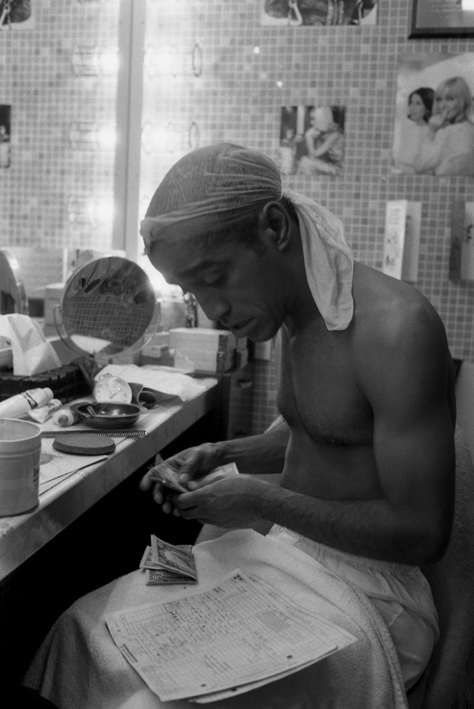 ammy Davis Jr. counts money backstage during Golden Boy' s Broadway run in 1964. He is shirtless and wearing a do-rag.