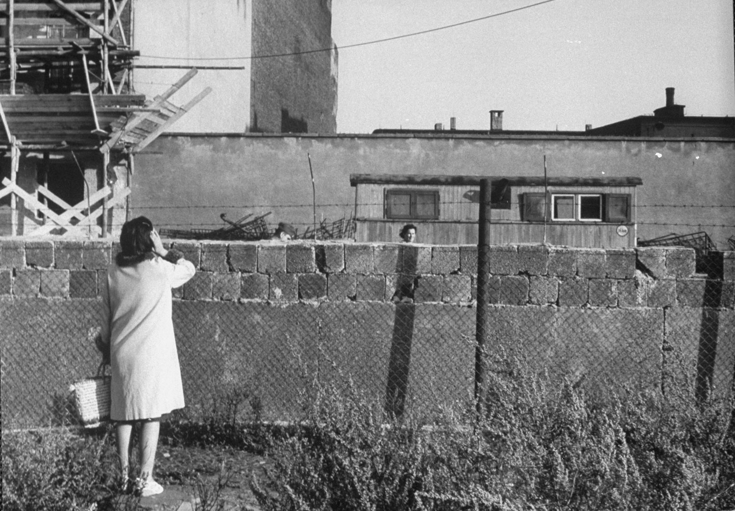 A mother and her daughter talk over the Berlin Wall.