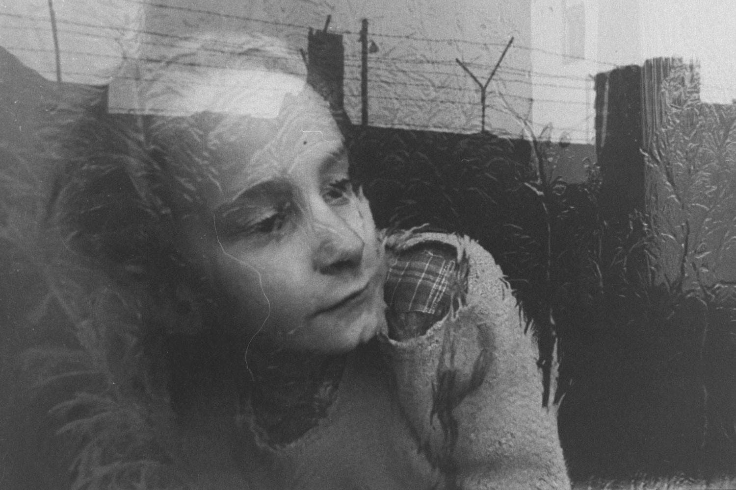 A girl looks through a frosty window at the Berlin Wall
