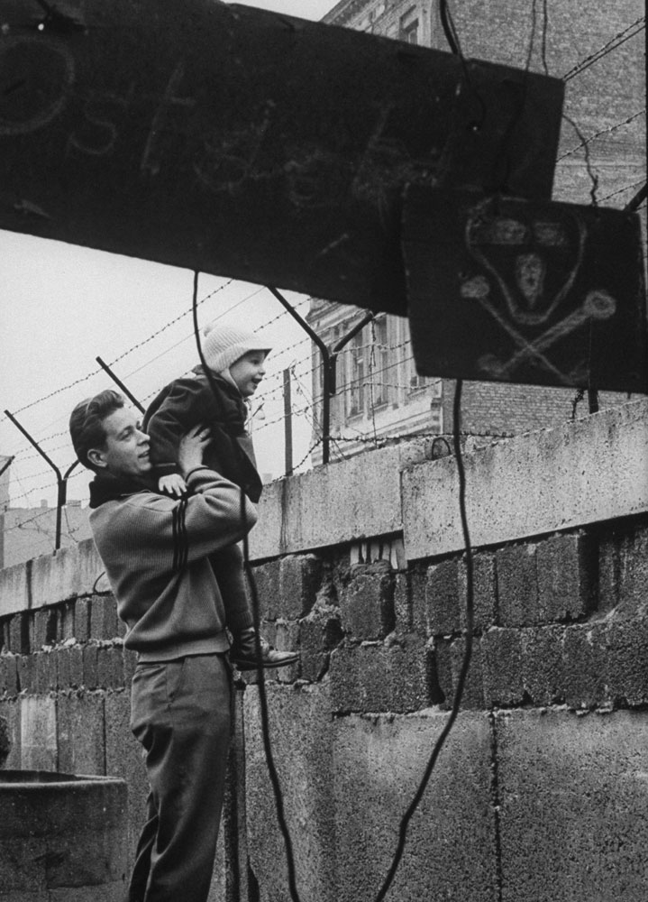 A West German man boosts up his son to give him a view of the other side of the Berlin Wall.