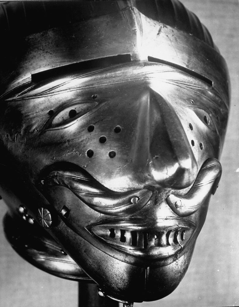 A helmet in the Hall of Armor feature stylized eyes, teeth, mouth and moustache at the Metropolitan Museum of Art.