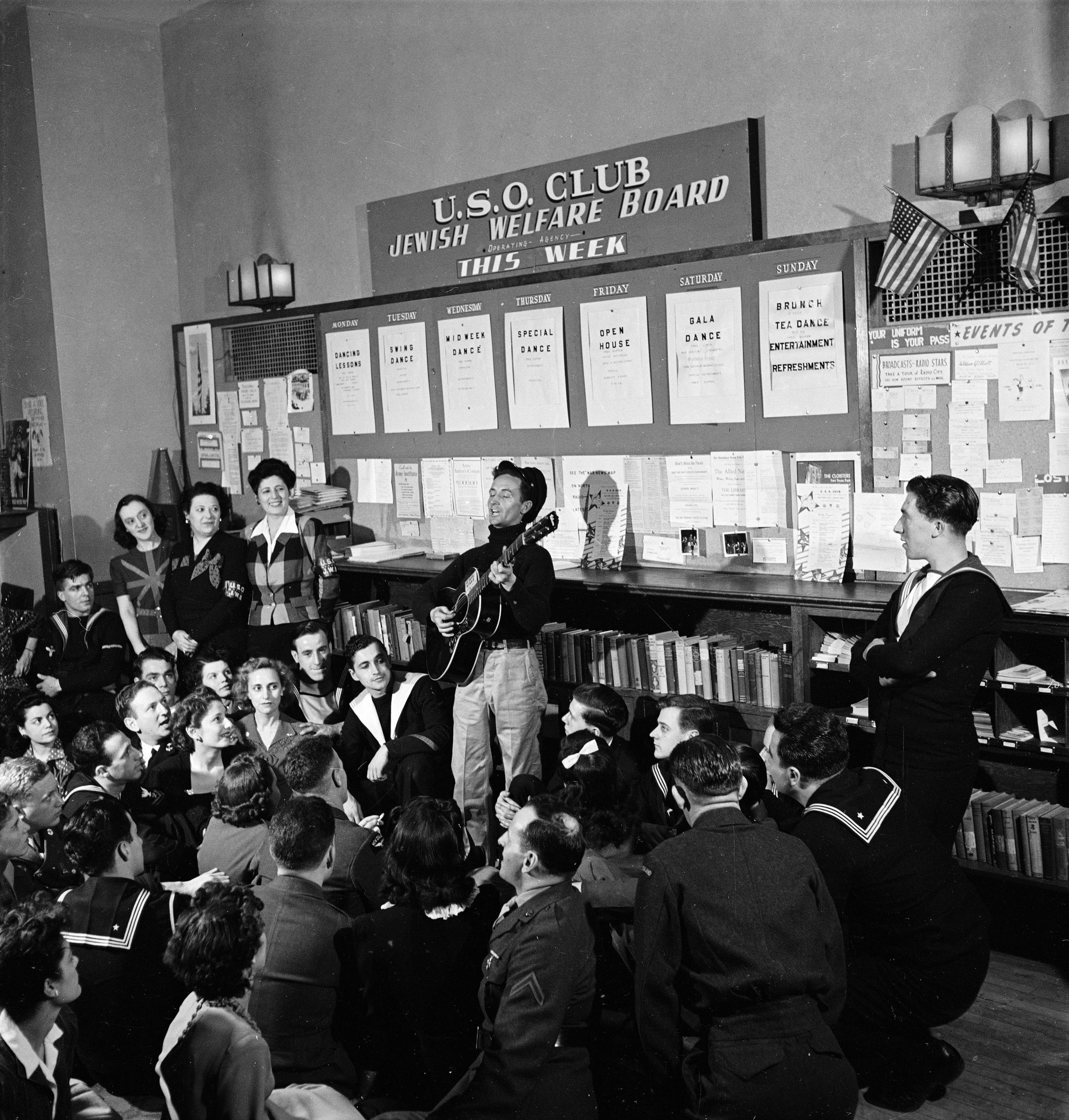 Woody Guthrie sings to sailors at a USO club, New York, 1943.