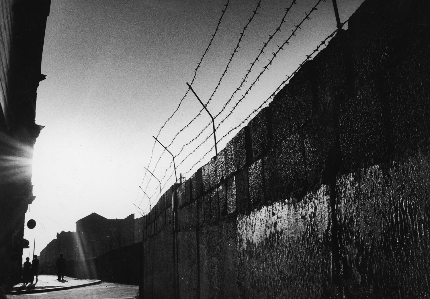 Sunlight shines on the barbed wire and blocks of the Berlin Wall