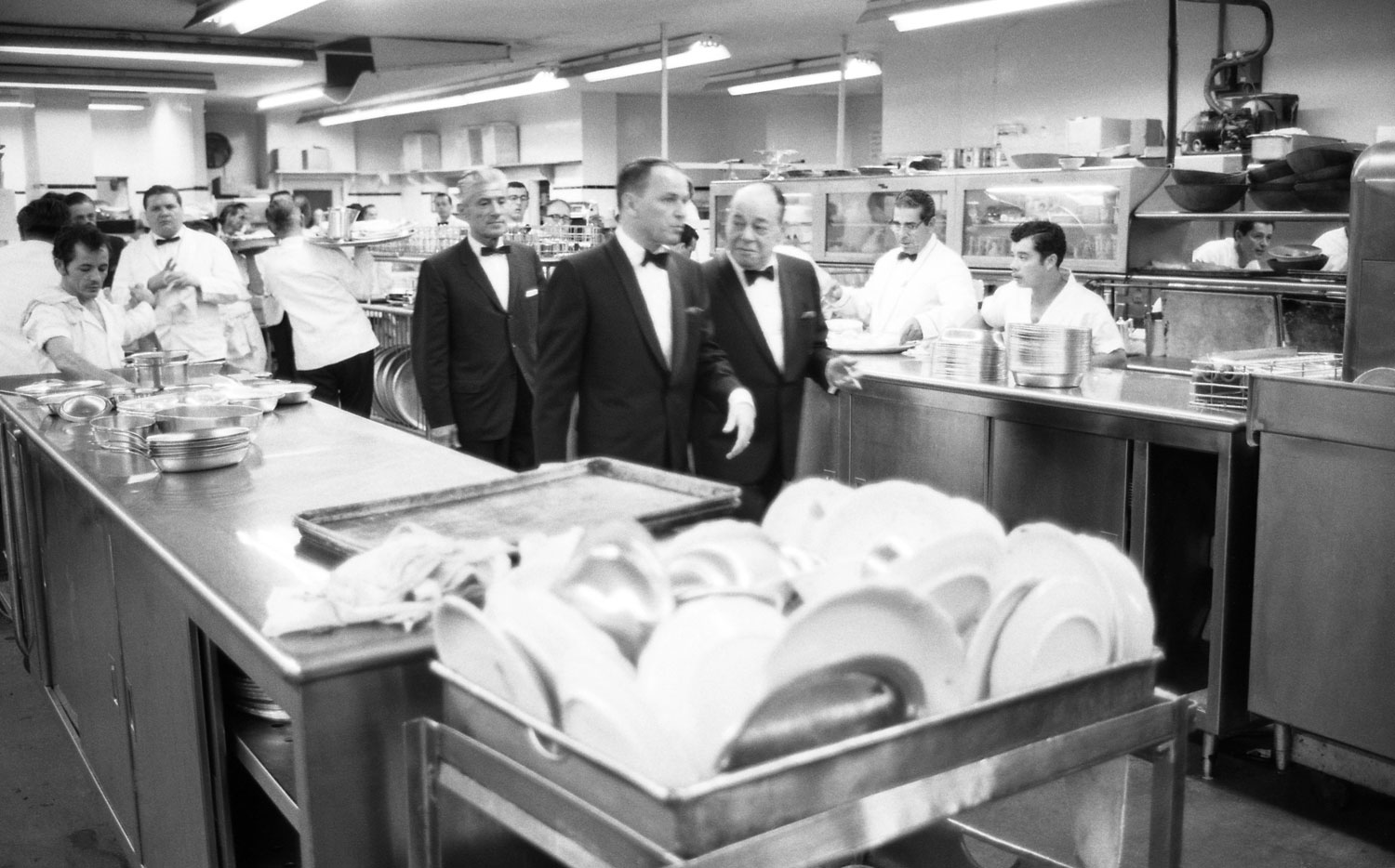 Frank Sinatra and Joe E. Lewis walk through the kitchen to get to the stage at the Eden Roc Resort in Miami in 1958.