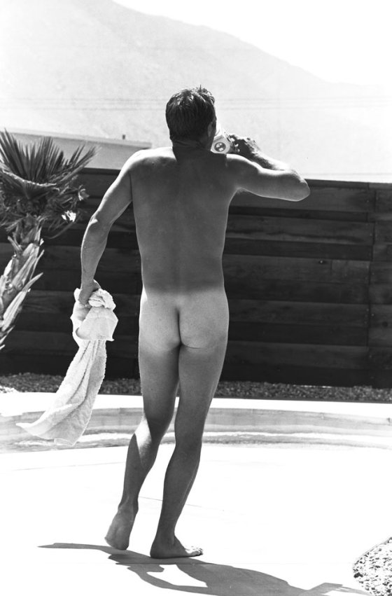 Steve McQueen walks around his pool naked in Hollywood in 1963. He his holding a towel.