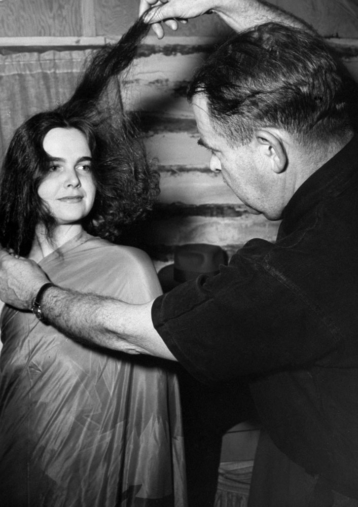 William Seabrook adjusts the rented West Indian robe worn by (in LIFE's words) "dark handsome" Florence Birdseye and shows her how to dress her hair for the hexing ceremony.