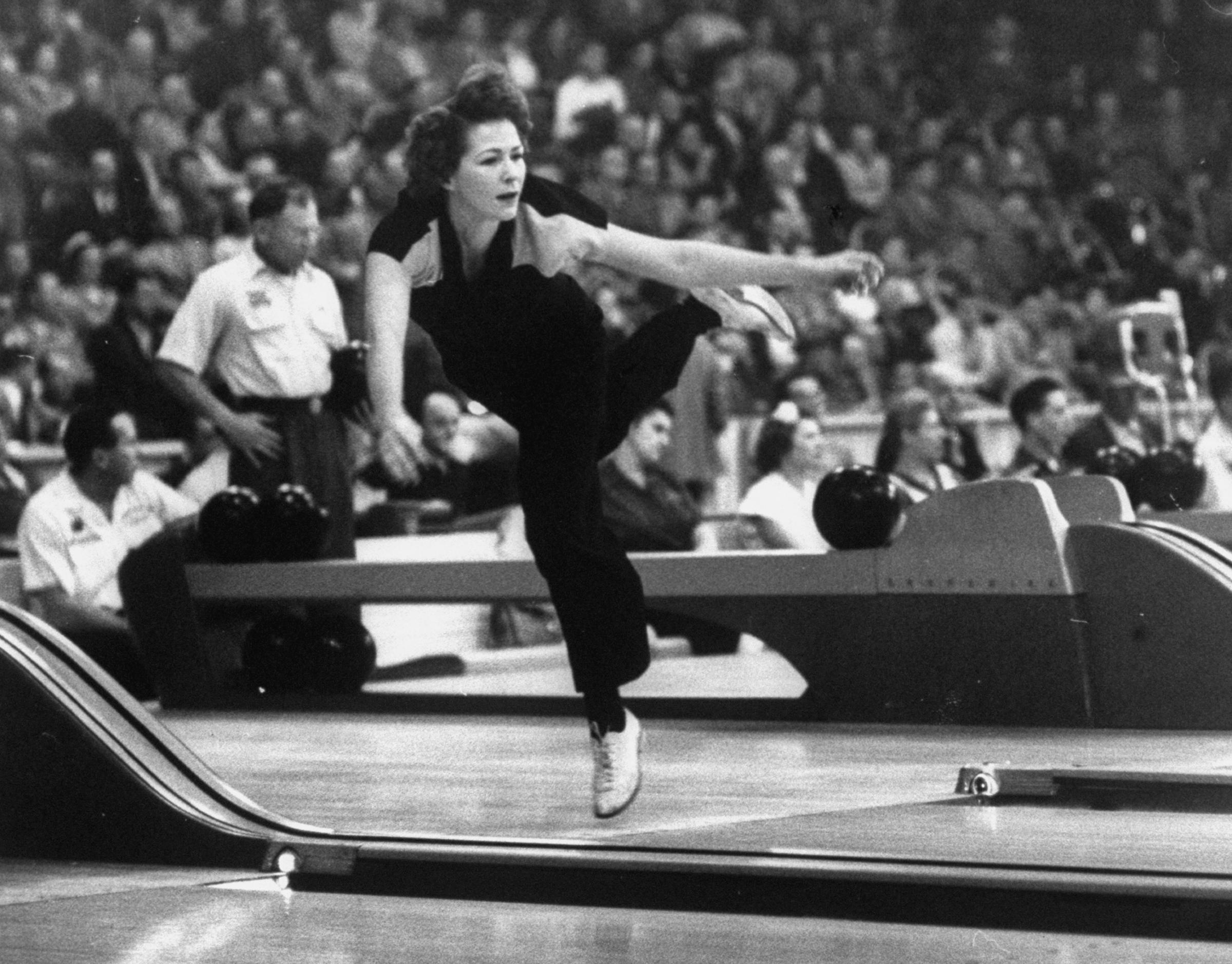Dorothy Crouch, balanced on one foot at the end of her stride, releases the ball in a preliminary match during a nine-day championship tournament.