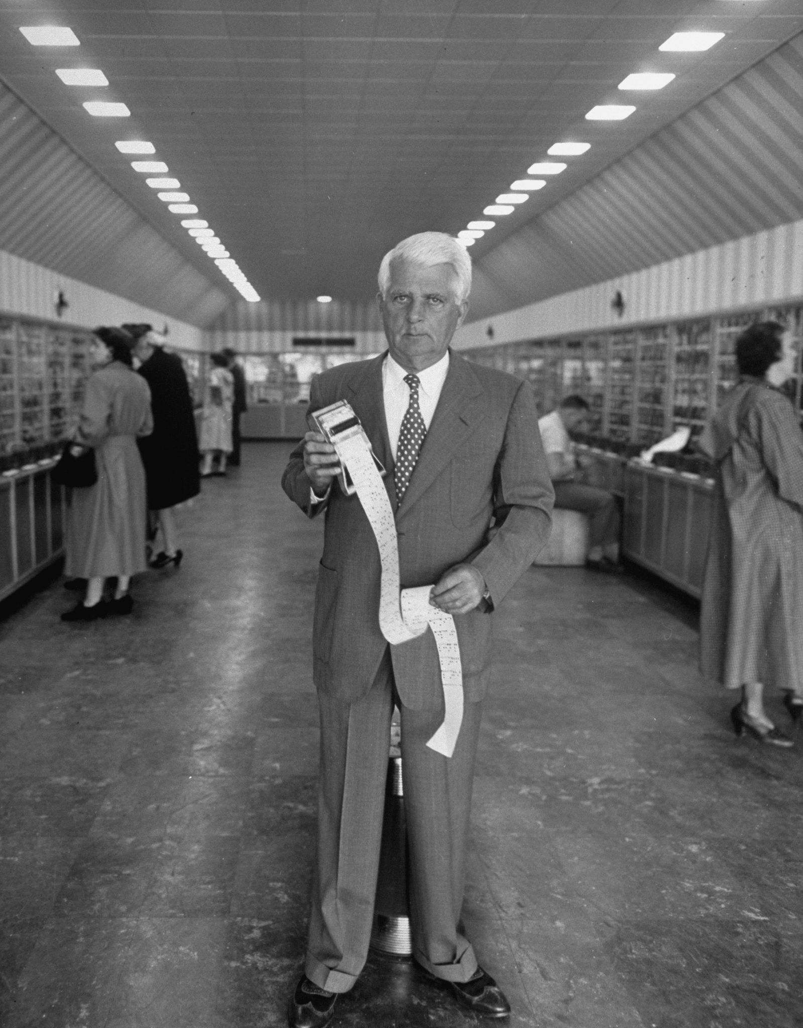 Clarence Saunders stands with the ticker-tape technology at the heart of Keedoozle, his fully automated grocery store, Memphis, Tenn., 1948.