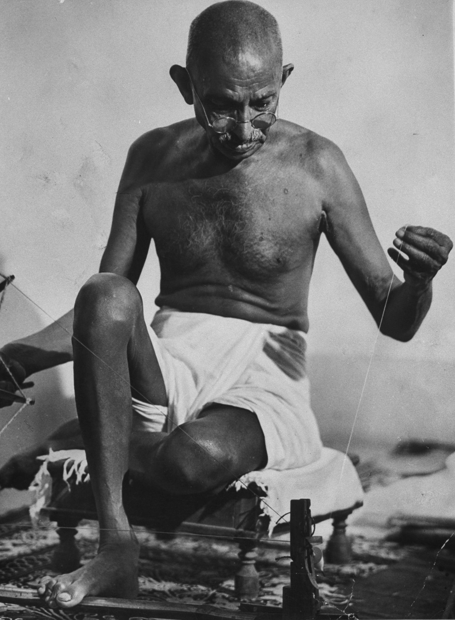 Mohandas Gandhi works at his spinning wheel
