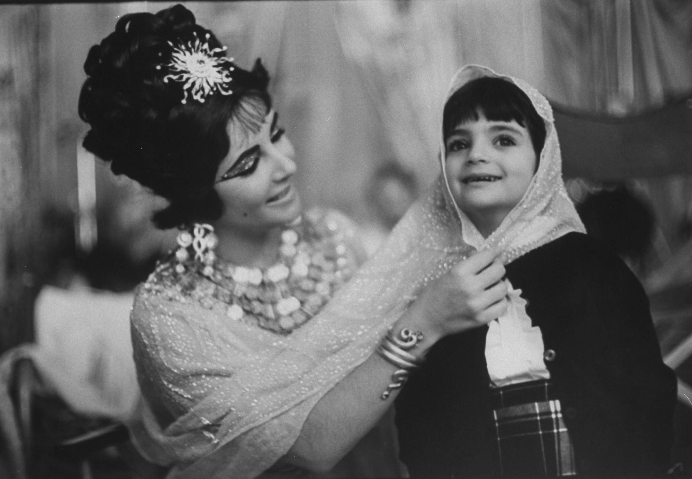 Elizabeth Taylor in costume on the Rome set of Cleopatra plays with daughter Liza in 1962