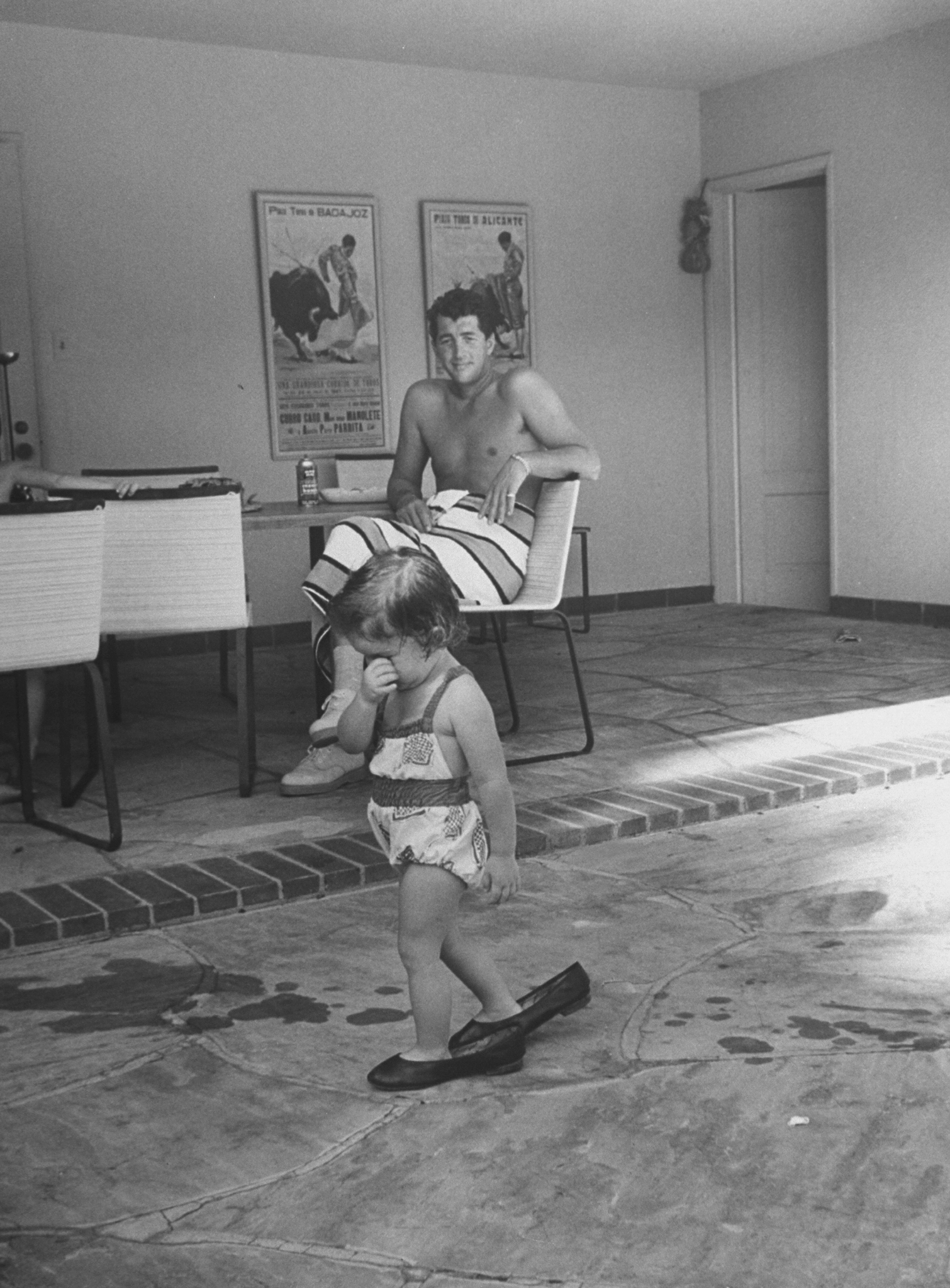 Gina Caroline Martin tries on father Dean Martin's shoes as he watches in background at home in Beverly Hills in 1958