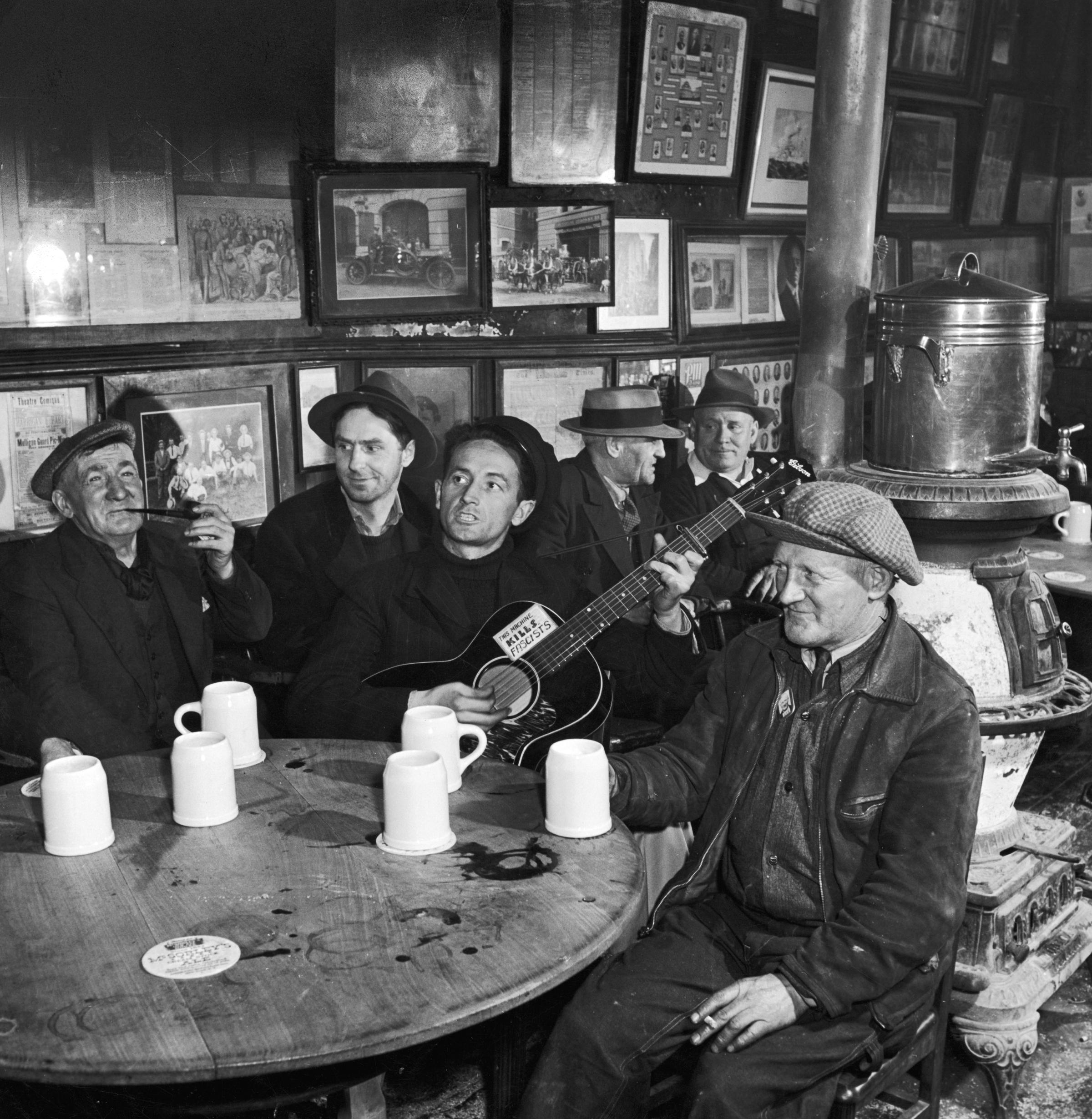 Woody Guthrie at McSorley's Old Ale House, still standing today in the East Village, New York City, 1943.