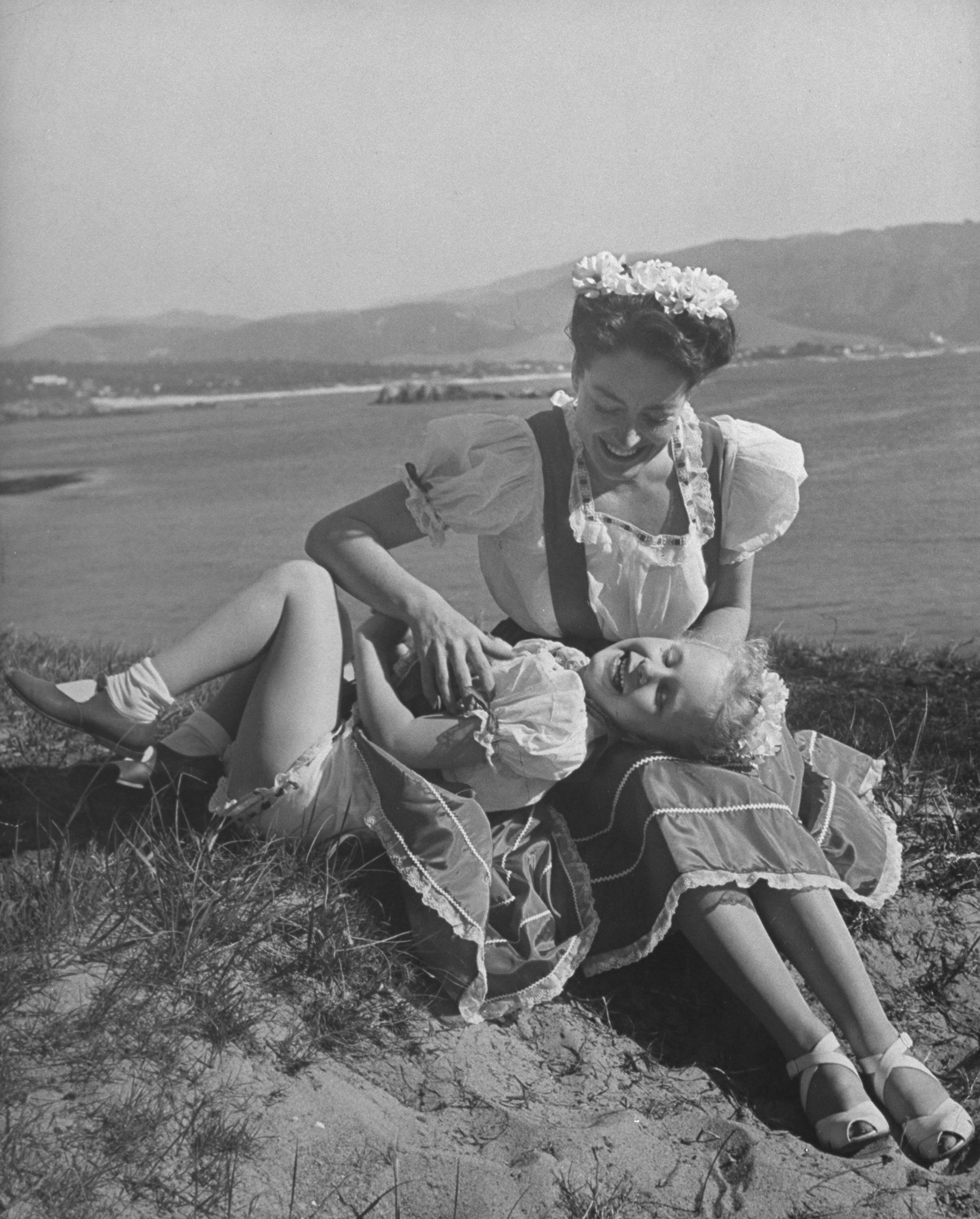 Joan Crawford with daughter Christina Crawford laying on lap in Monterey, California in 1945