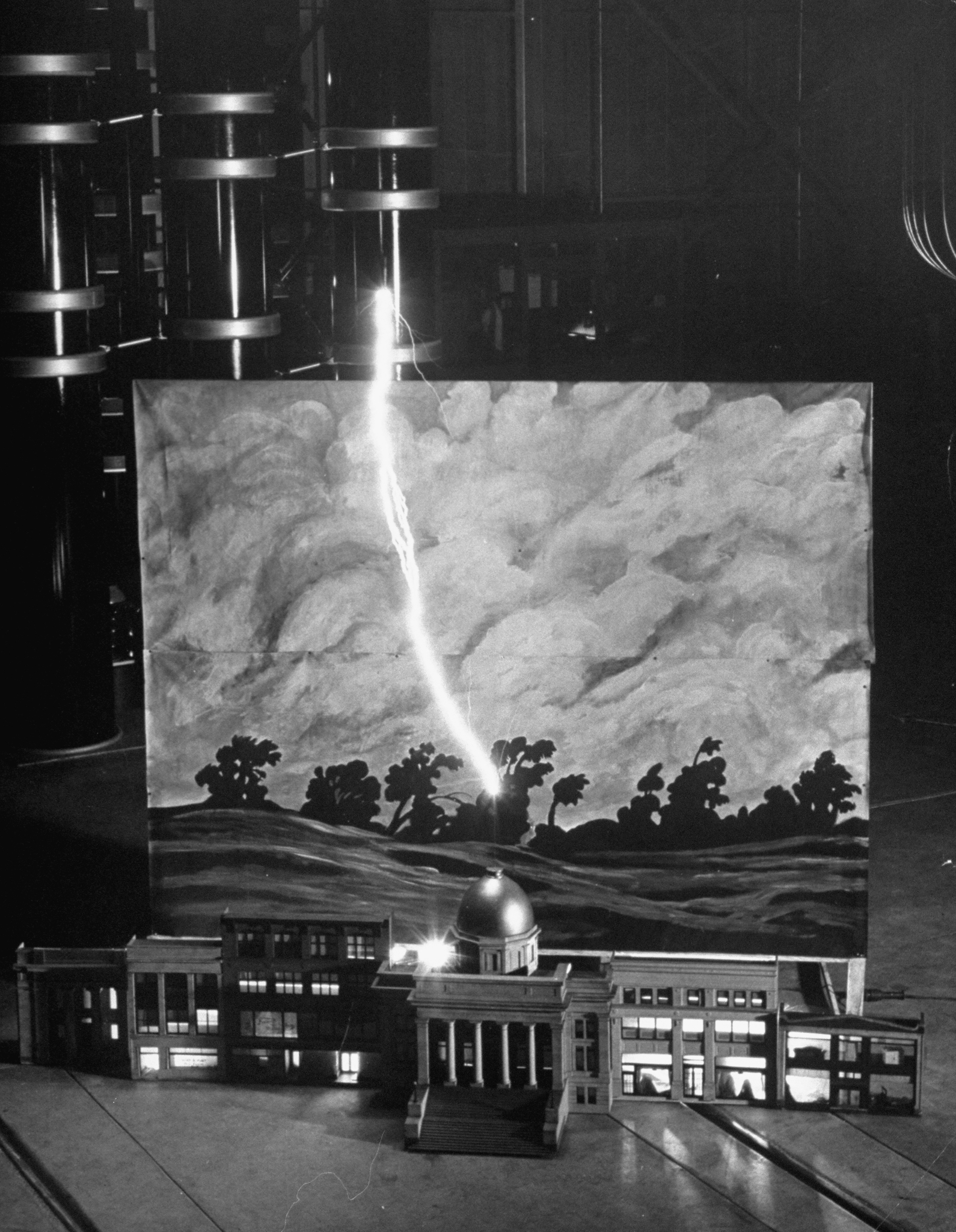 A man-made lightening bolt strikes a metal rod atop a model courthouse, 1949.