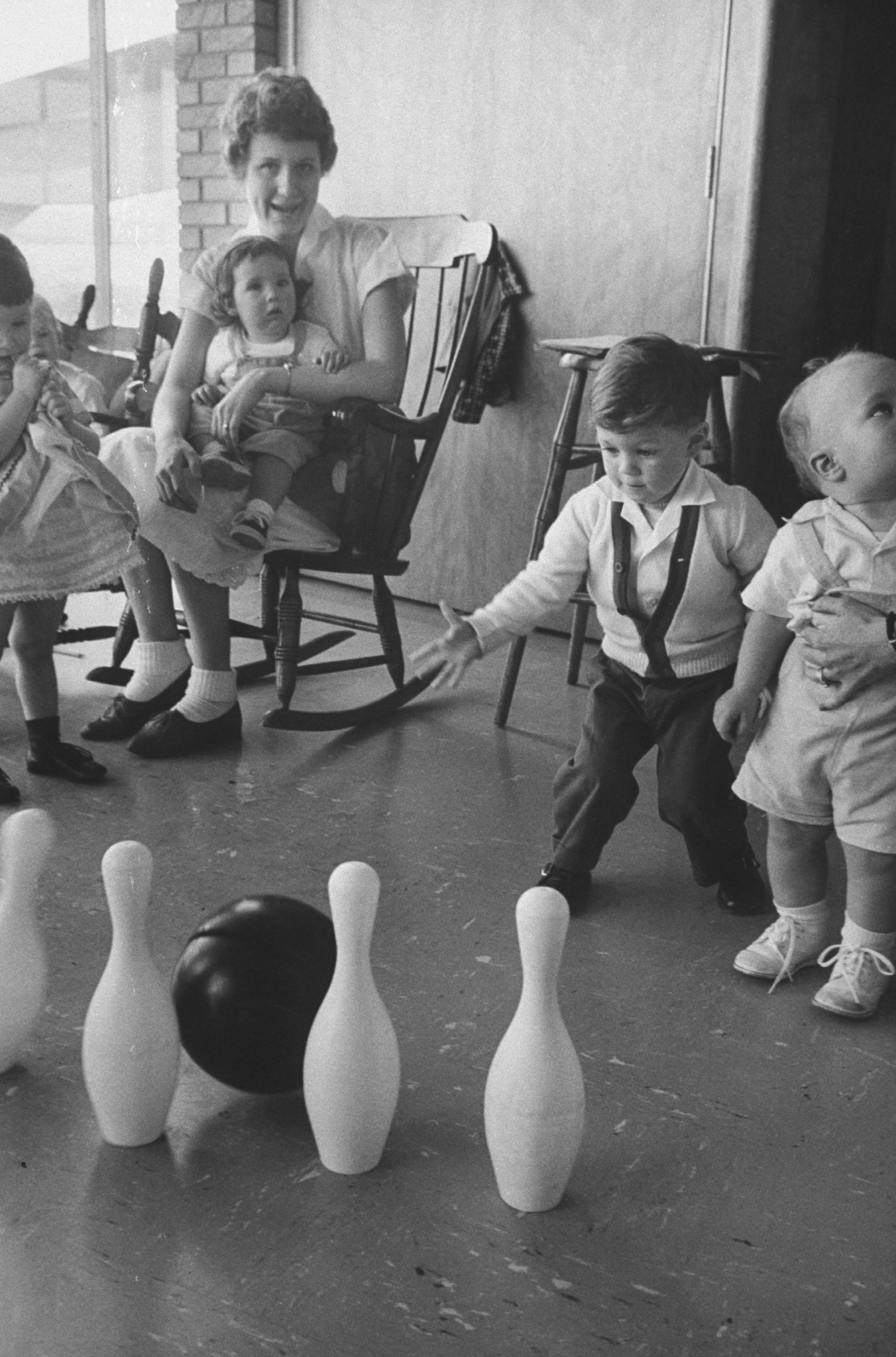 Children play with a plastic bowling ball and pins, provided in order to prevent them from interrupting their mothers as they bowl, at a nursery at the Hart Bowl
