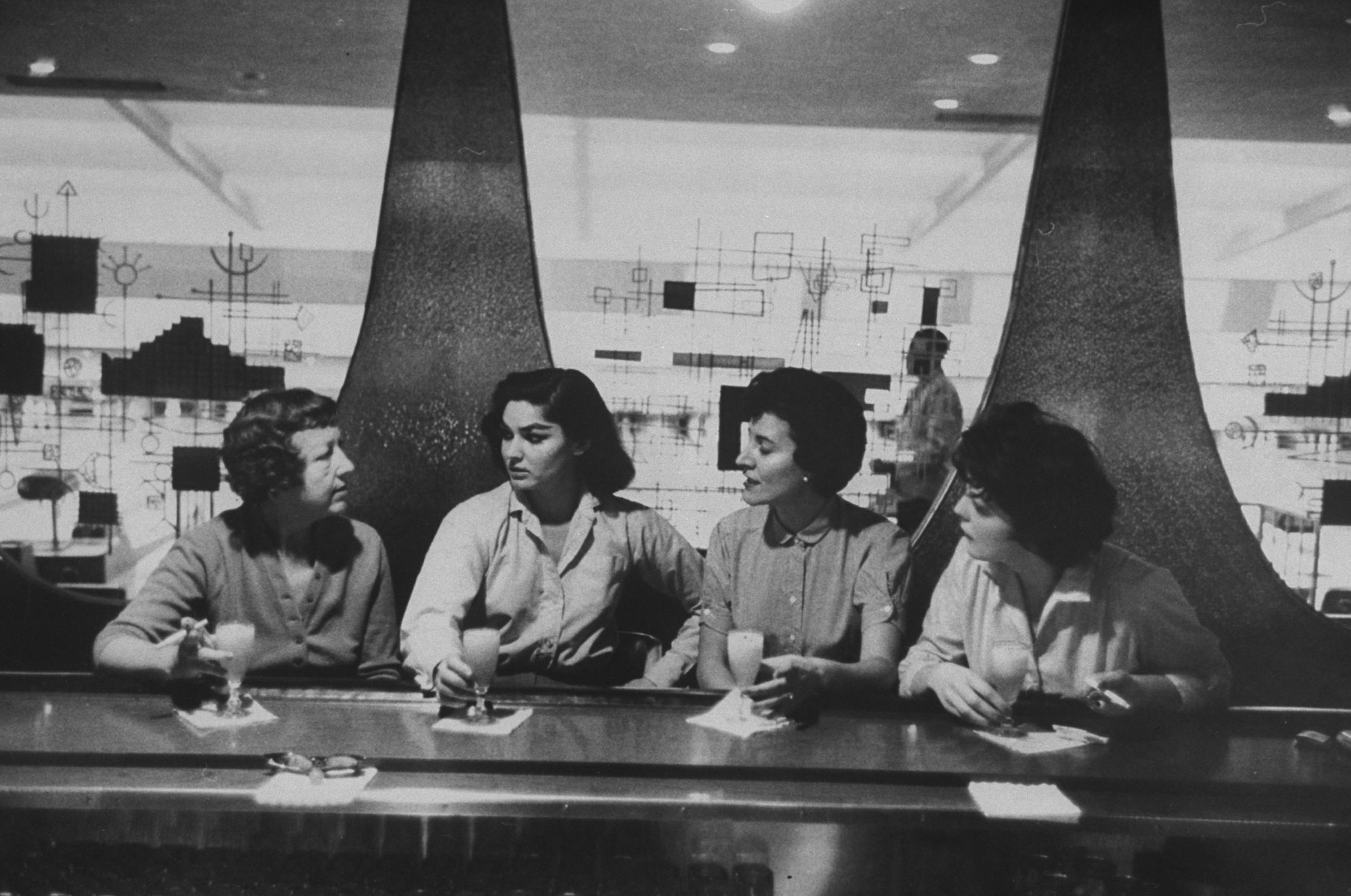 Women at a bowling alley bar celebrate their high-scoring game with a round of drinks.