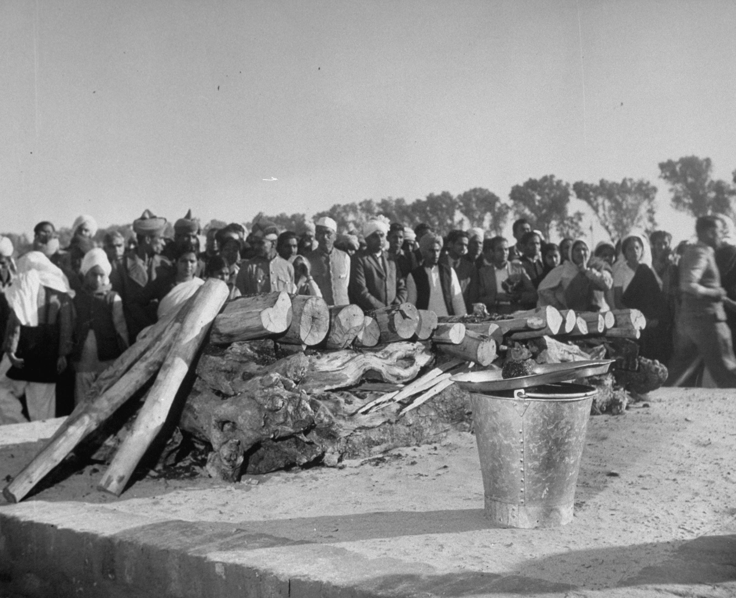Mourners gather around wood stacked for Mohandas Gandhi's funeral pyre in 1948.