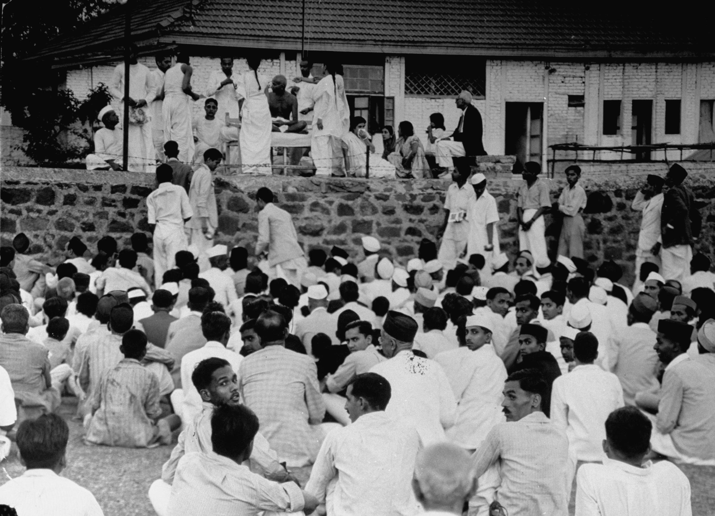 In 1946, Gandhi (seated on a bed at top) leads evening prayers surrounded by his devoted disciples and followers.
